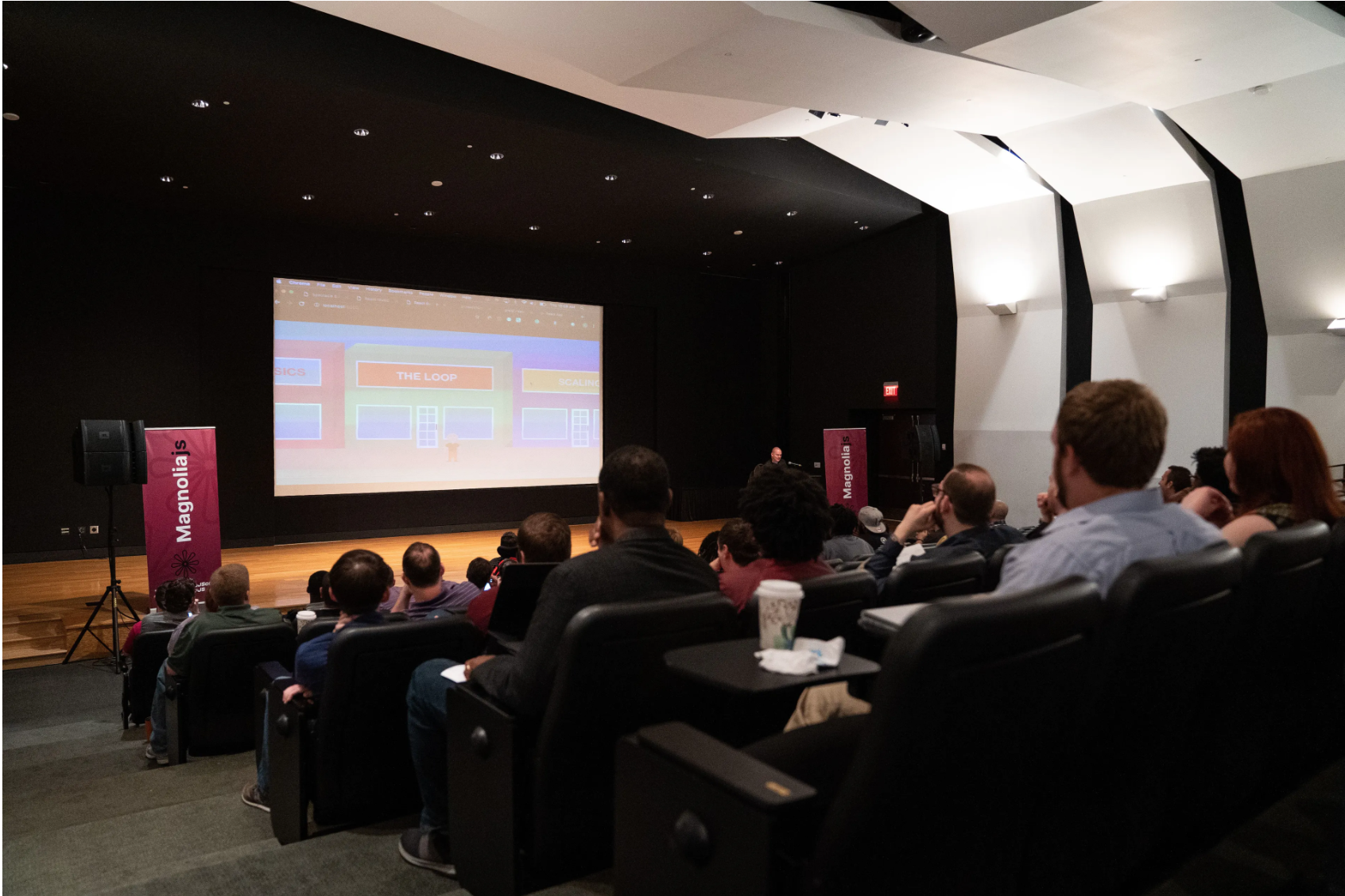 Participants sit in a theater and watch a projection